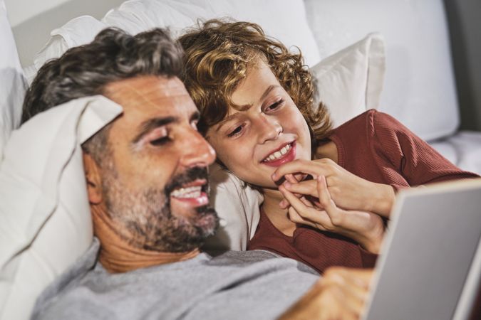 Curious boy and father reading book on bed