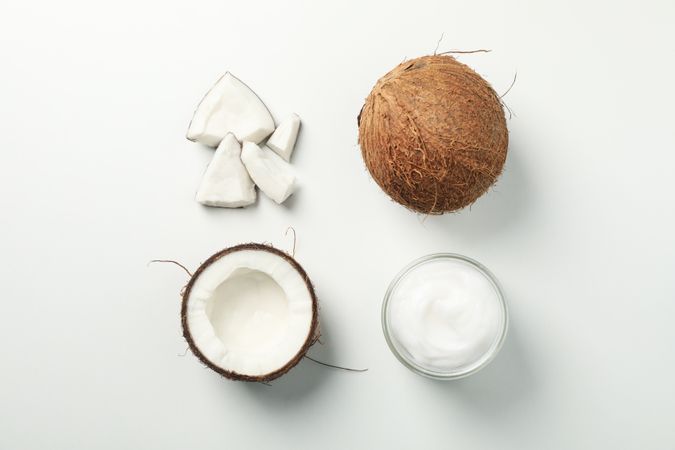 Flat lay with coconut and cosmetic on plain background, top view