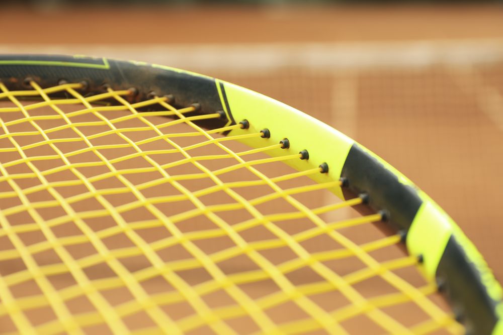 Tennis racquet against clay court, close up