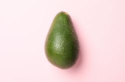 Ripe fresh avocado on pink background, close up