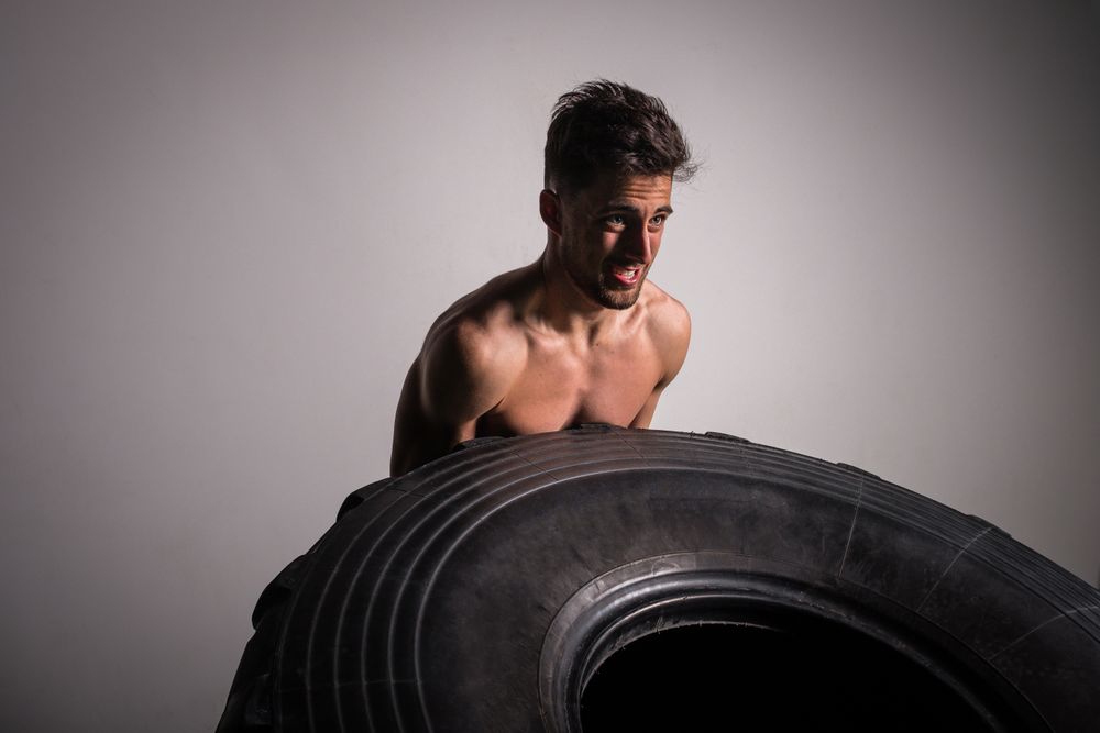 Man flipping big tires in gym