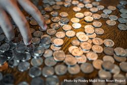 A hand over a table scattered with coins 0LBag4