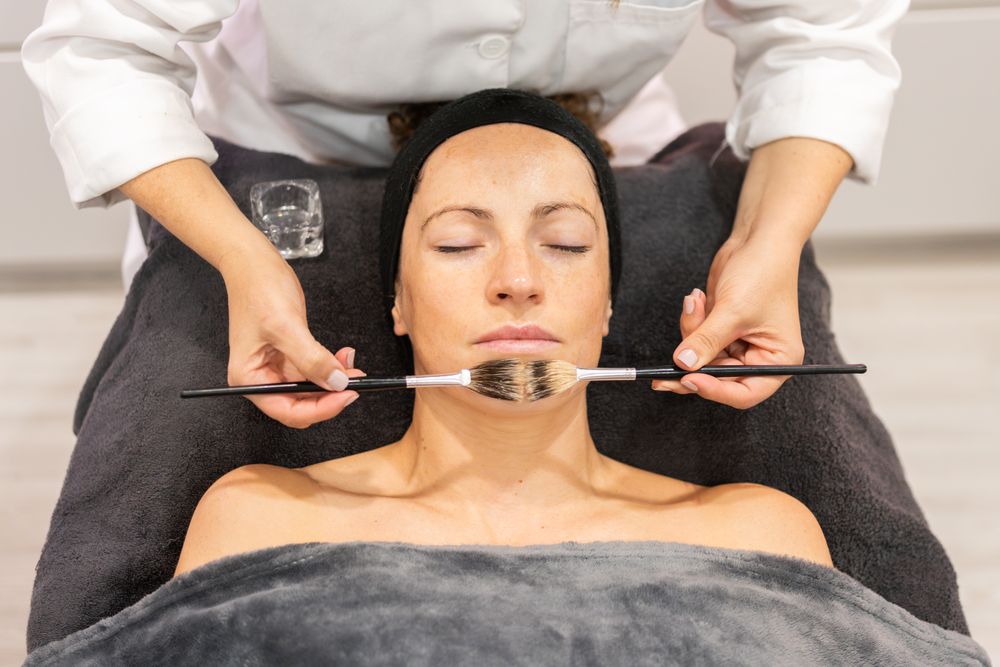 Beautician applying cosmetics to client in beauty center