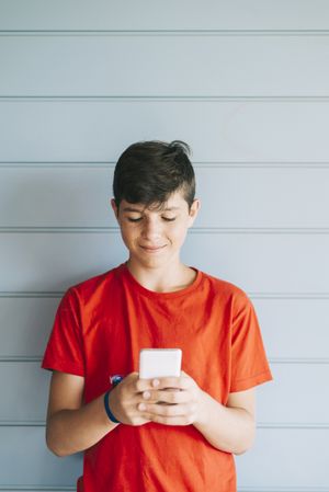Profile of a happy male teen texting on a smart phone