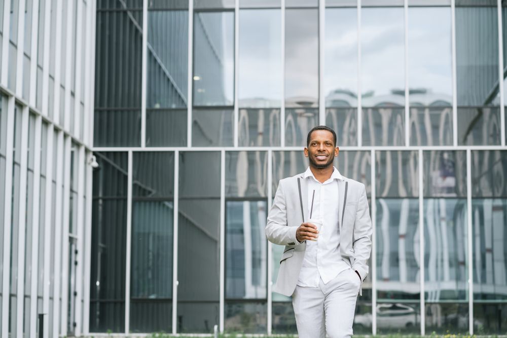 Black man with coffee standing in downtown
