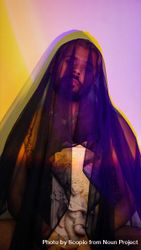Portrait of topless man wearing purple veil holding angel statue bGXpa0