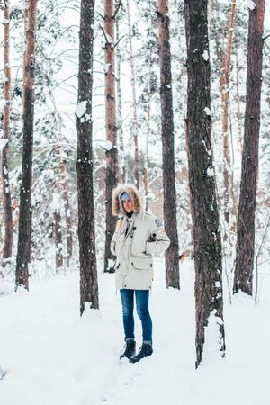 Man in parka and jeans outside in snowy forest