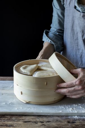 Cook preparing buns in bamboo steamer
