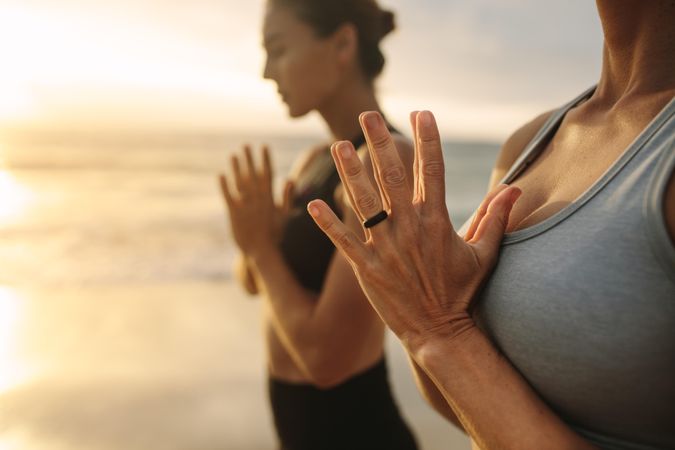 Close up of woman meditating at the beach with joined hands
