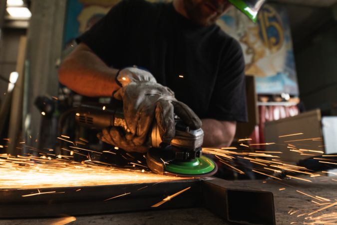 Male worker using electric grinder in workshop