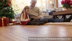Grey haired man with granddaughter using digital tablet at home 5qkvQo
