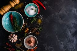 Spices, herbs and salt on dark counter with copy space