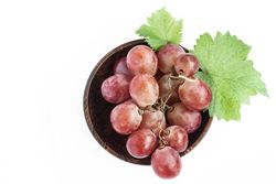 Red grape in wooden bowl, closeup, isolated on blank background
