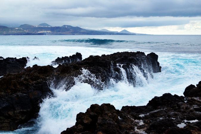 blue waves of ocean with foam texture against rocks
