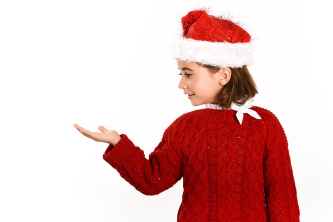 Girl in Christmas outfit with hand presenting copy space