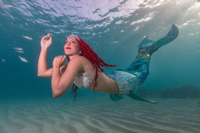 Redhead fairytale female mermaid swimming underwater