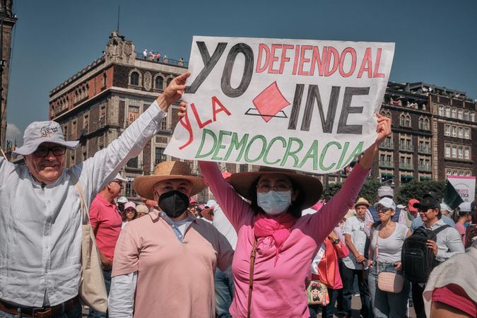 Mexico City, Mexico - February 26th, 2022: Woman in pink shirt holding up protest sign