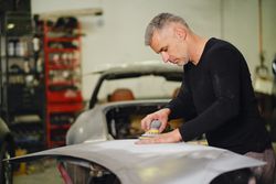 Mechanic grinding paint from car detail