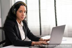 Woman wearing headphones while typing on laptop 5pd1v5