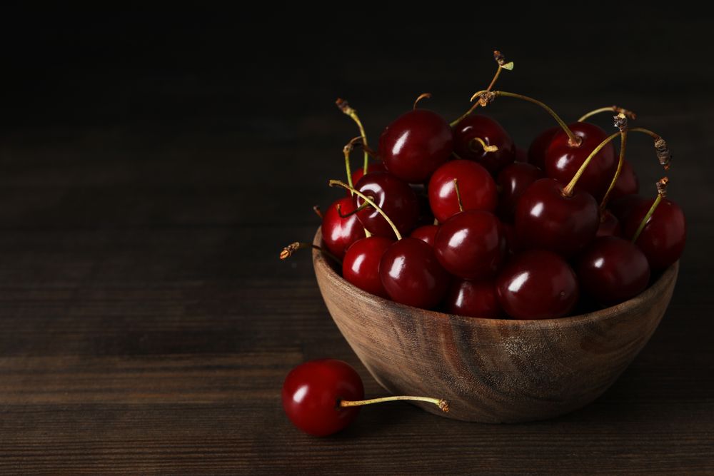 Ripe cherry fruits in a bowl on a wooden background