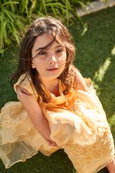 Dreamy girl sitting on green lawn in park