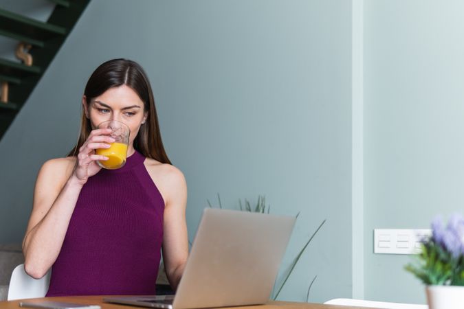Cheerful woman browsing laptop in living room