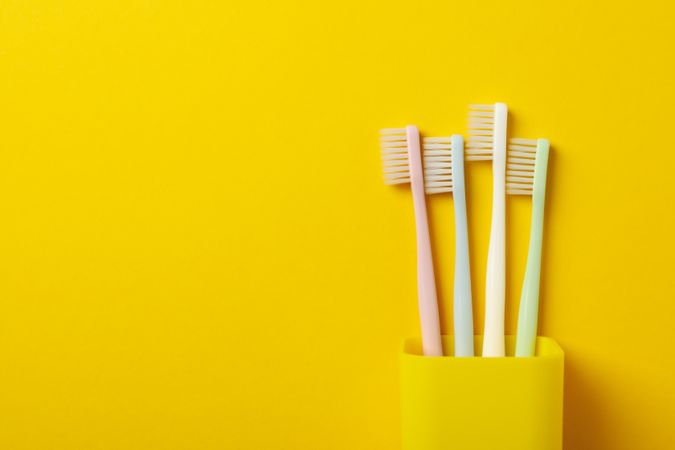 Toothbrushes on yellow background, space for text