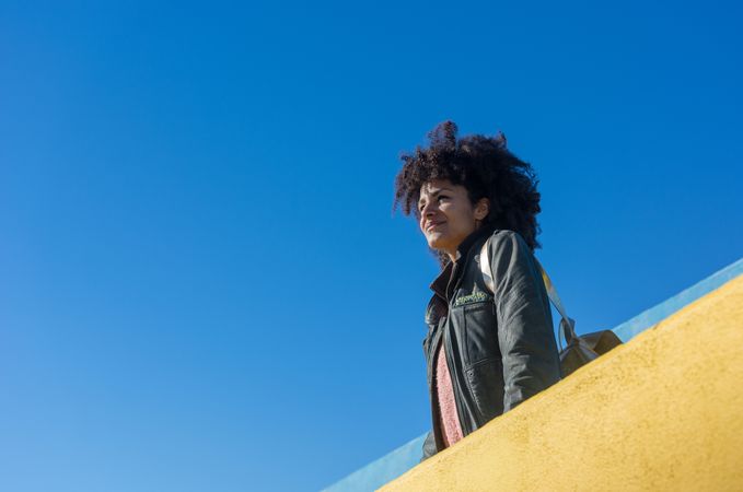 Black woman with afro hair leaning against brightly colored wall
