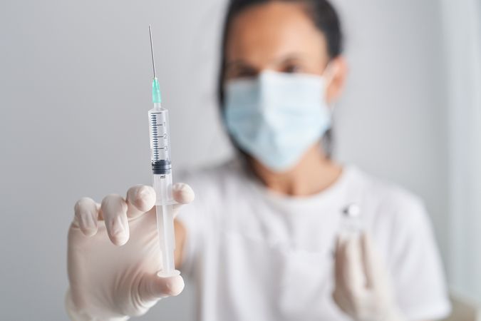 Woman in face mask holding syringe