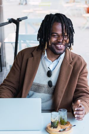 Serious Black man with espresso and glass of water in cafe
