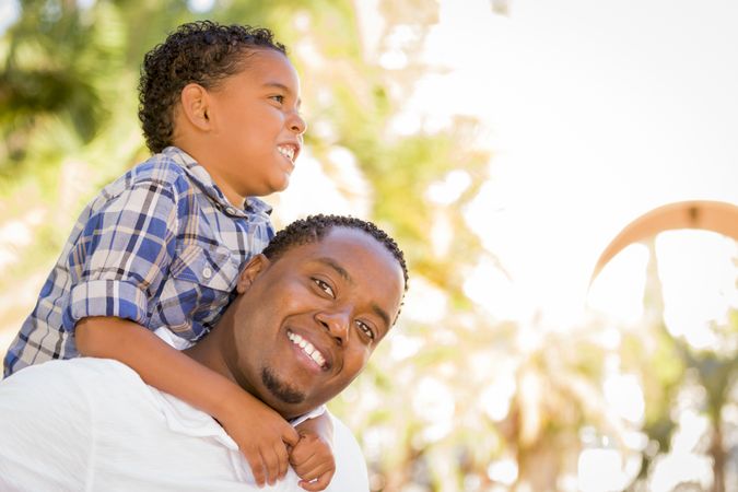 Father and Son Playing Piggyback Outdoors On Sunny Day
