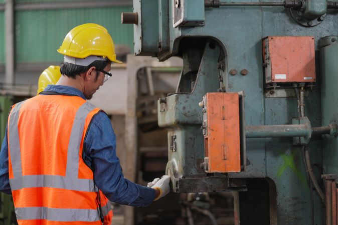 Man pressing button on machinery in factory