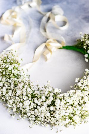 Headdress with ribbon of gypsophila paniculata flowers on marble table