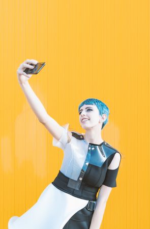 Cheerful futuristic woman taking selfie with smartphone