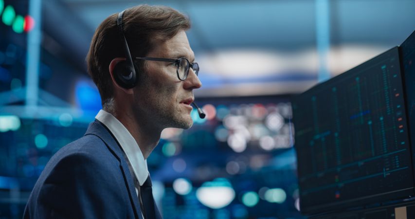 Stockbroker Talking with Business Clients on a Call, Working on Computer, Speculating on Buying Shares for Trading