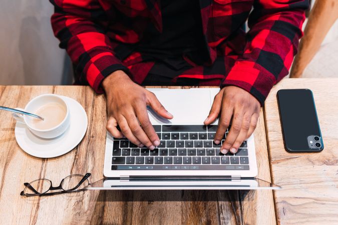 Anonymous Black man working on laptop in cafe