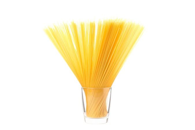 Pasta in glass isolated on light background. Uncooked whole wheat pasta