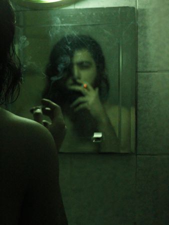 Reflection of a person on the mirror smoking