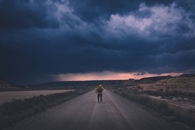 Man standing on road and looking at impressive evening sky