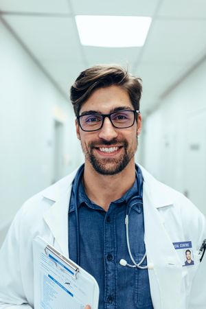 Portrait of happy doctor standing in hospital corridor