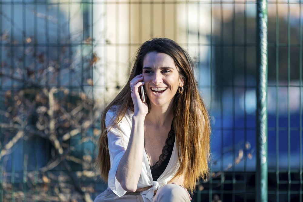Laughing woman wearing casual clothes talking on phone