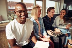 Portrait of happy Black man on sofa with his work colleagues