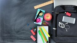Back to school concept with modern technology and traditional objects on chalkboard, copy space