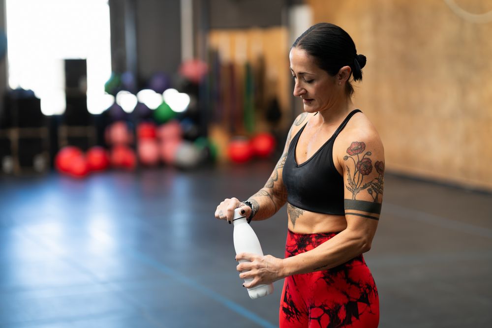 Woman about to drink water after training in gym