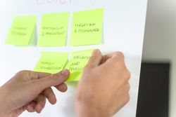 Person brainstorming with sticky notes on a whiteboard during a workshop.