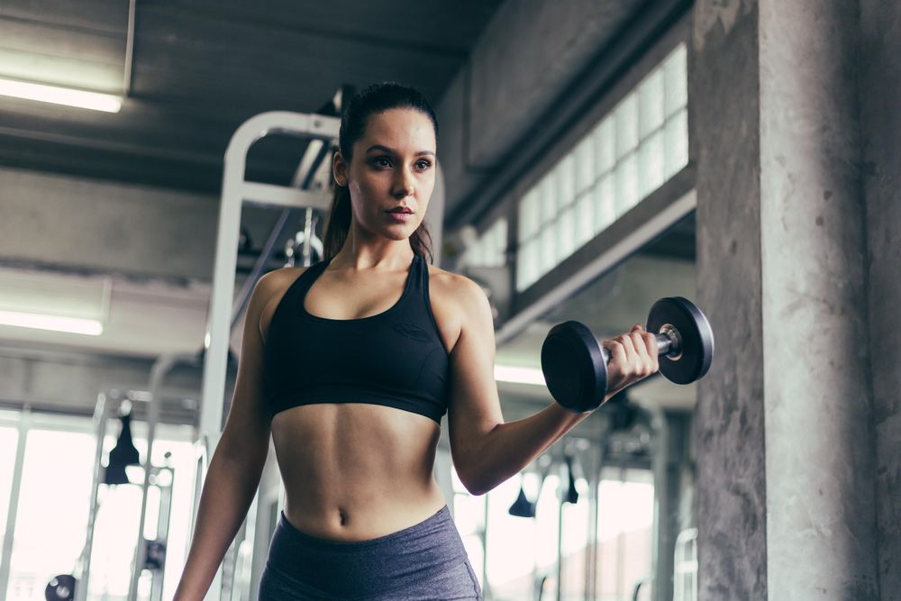 Active sporty woman lifting dumbbell