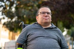 Portrait of proud man sitting in wheelchair under tree
