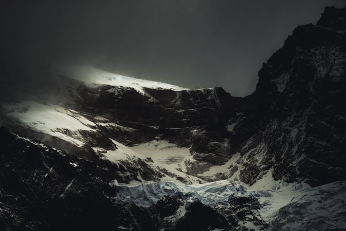 Harsh mountain snowy peak shrouded in fog