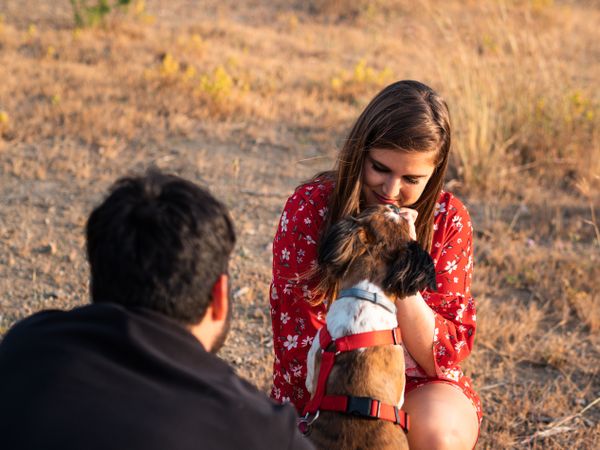 Happy couple with friendly cute dog resting outdoors