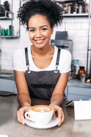Smiling barista serving cappuccino